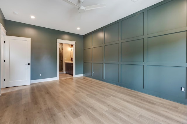 unfurnished bedroom with recessed lighting, a decorative wall, light wood-style floors, ensuite bath, and baseboards