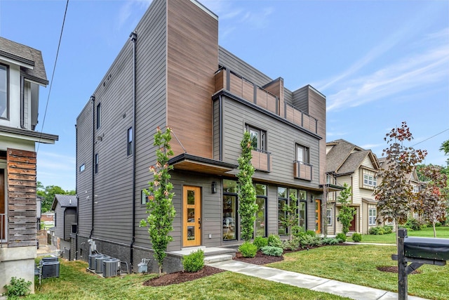 view of front of property with a front yard and central AC unit