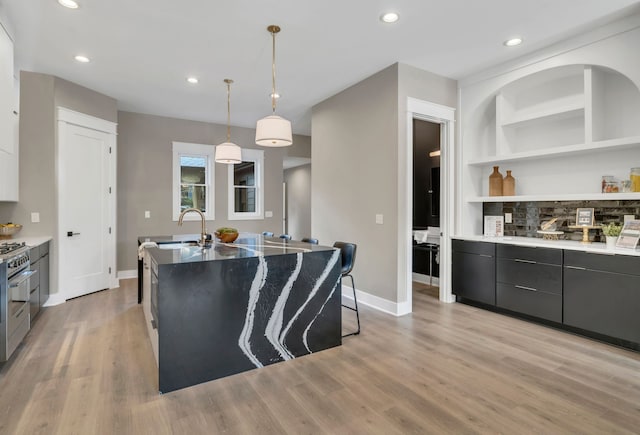 kitchen featuring decorative light fixtures, light hardwood / wood-style flooring, built in features, and a spacious island