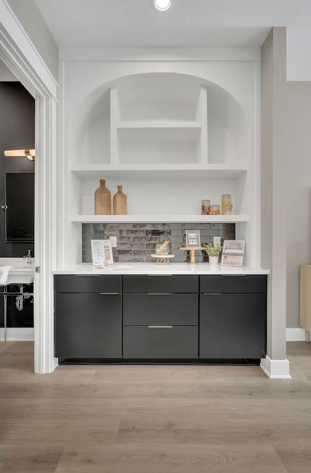 bar featuring gray cabinetry, sink, light hardwood / wood-style flooring, and built in shelves