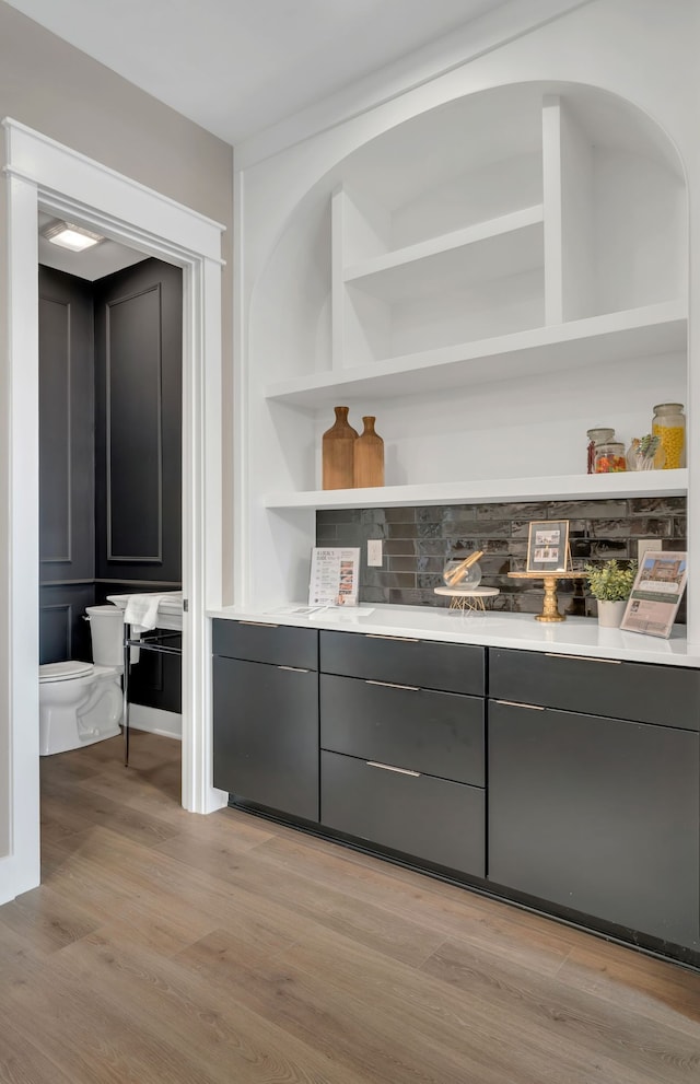 bar with built in features and light wood-type flooring