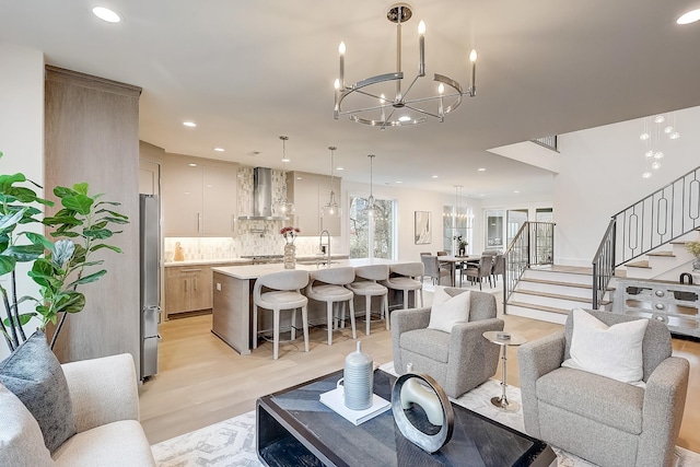 living room featuring sink, an inviting chandelier, and light hardwood / wood-style floors