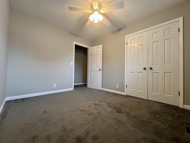 unfurnished bedroom featuring ceiling fan, a closet, and dark colored carpet