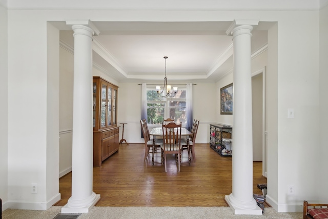 dining area featuring a tray ceiling, ornate columns, hardwood / wood-style floors, and crown molding