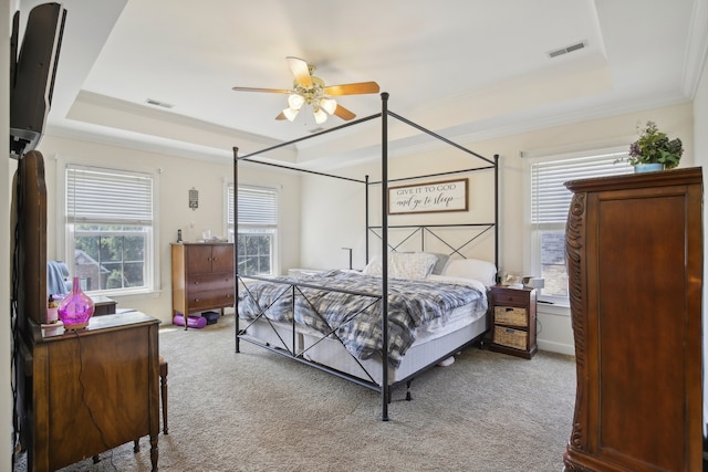 carpeted bedroom with ceiling fan, crown molding, and a tray ceiling