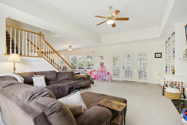 carpeted living room with ceiling fan, crown molding, and a tray ceiling