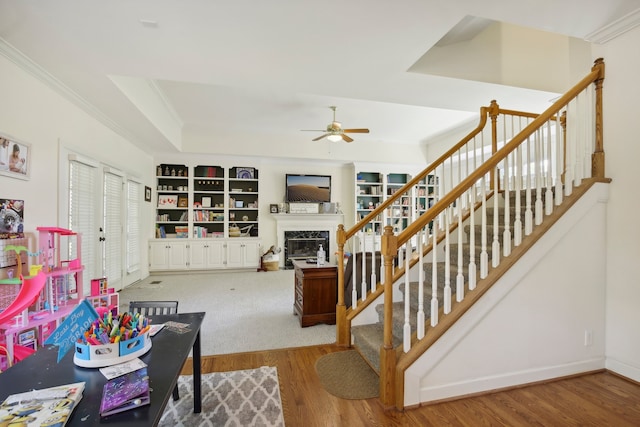 living room with a high end fireplace, hardwood / wood-style floors, ornamental molding, built in features, and ceiling fan