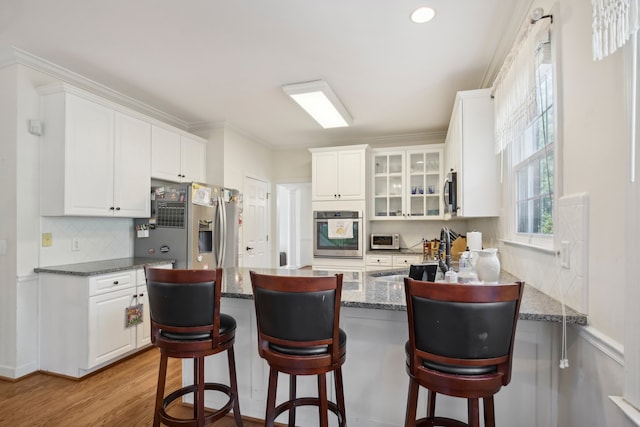 kitchen with white cabinets, a kitchen bar, stainless steel appliances, sink, and kitchen peninsula