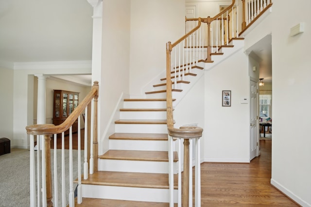 staircase featuring crown molding, decorative columns, hardwood / wood-style flooring, and a wealth of natural light