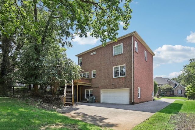 rear view of property featuring a garage, a lawn, and a deck