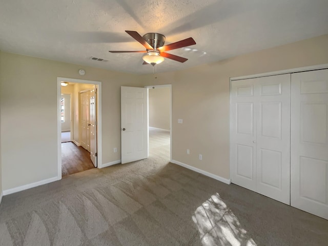 unfurnished bedroom with ceiling fan, a closet, dark carpet, and a textured ceiling