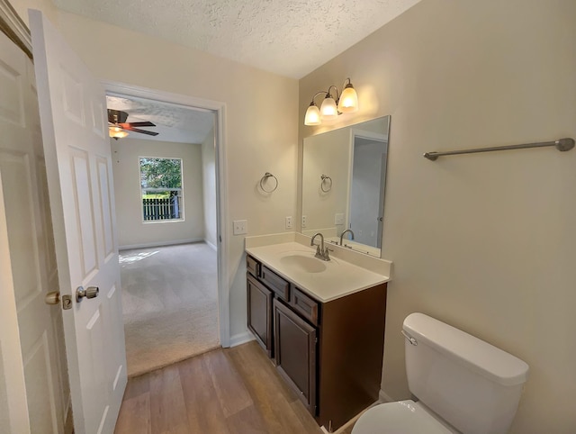 bathroom featuring vanity, a textured ceiling, ceiling fan, wood-type flooring, and toilet