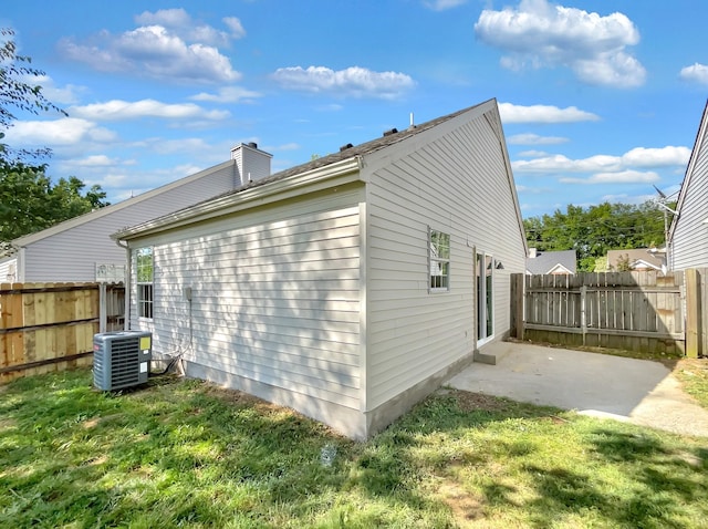 view of side of property with a patio, a yard, and central AC