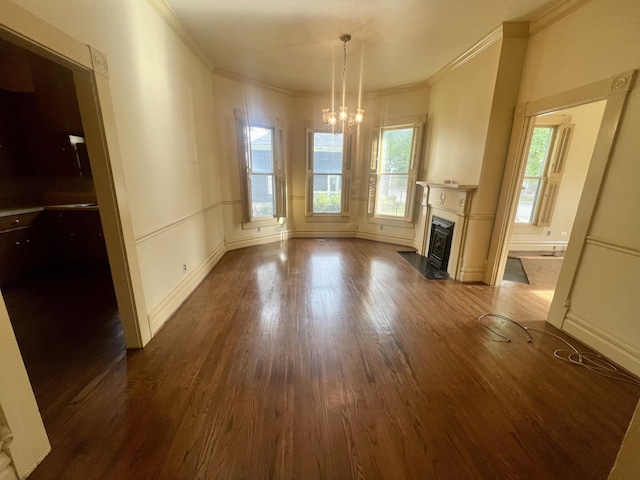 unfurnished living room with ornamental molding, dark wood-type flooring, and a chandelier