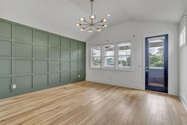 interior space with an inviting chandelier, vaulted ceiling, and light hardwood / wood-style floors