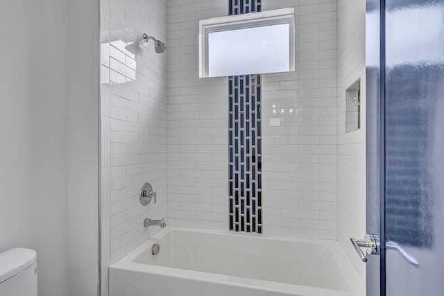 bathroom featuring toilet and tiled shower / bath