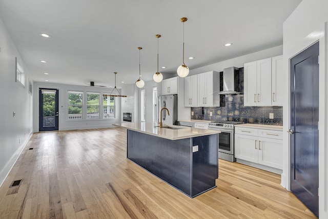 kitchen with white cabinetry, wall chimney range hood, and stainless steel appliances