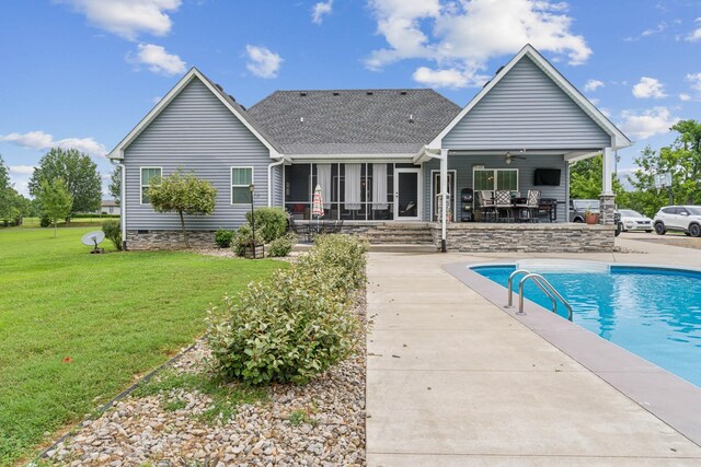 rear view of house with ceiling fan and a lawn