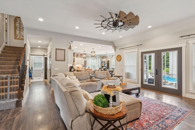 living room with ceiling fan with notable chandelier, french doors, dark hardwood / wood-style flooring, and a barn door