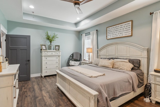 bedroom with a tray ceiling, ceiling fan, and dark wood-type flooring