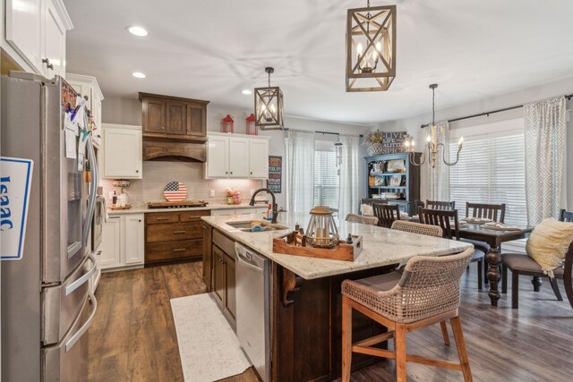 kitchen with hanging light fixtures, white cabinets, sink, appliances with stainless steel finishes, and dark wood-type flooring