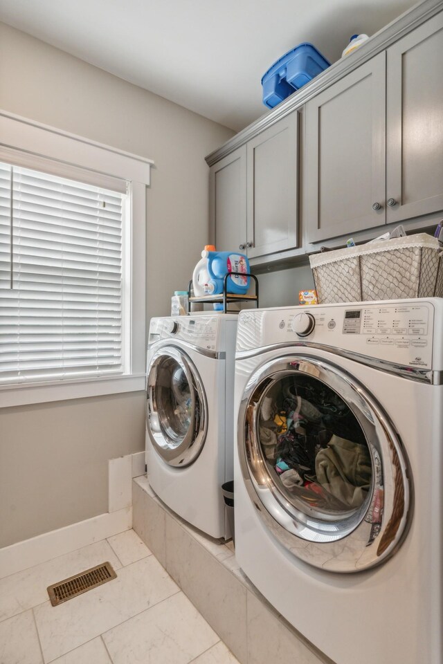 clothes washing area featuring light tile patterned flooring, independent washer and dryer, and cabinets