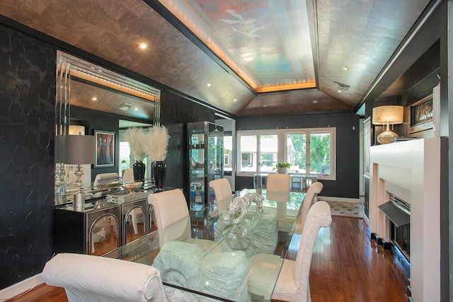 dining room featuring hardwood / wood-style flooring, vaulted ceiling, and a fireplace