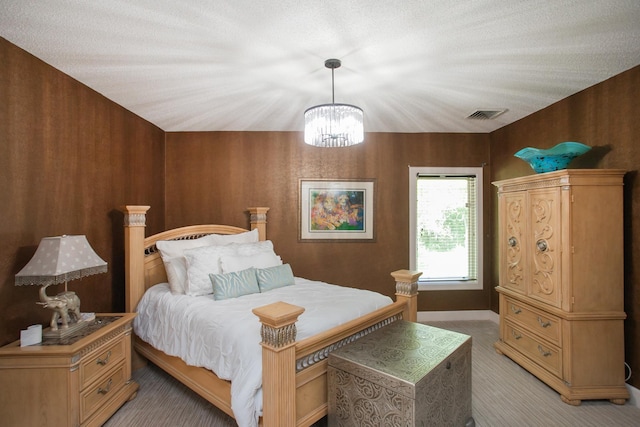 carpeted bedroom with an inviting chandelier and a textured ceiling