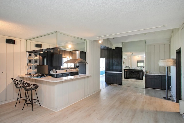 kitchen with light hardwood / wood-style floors, sink, kitchen peninsula, and extractor fan