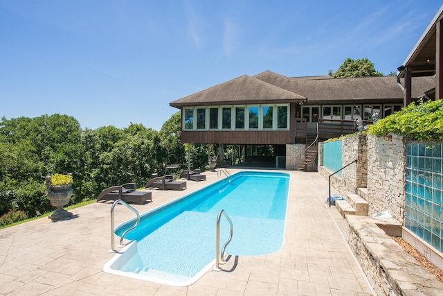 view of swimming pool with a sunroom and a patio