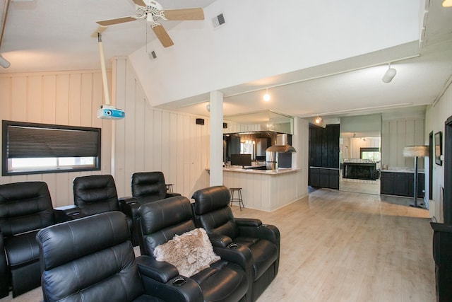 home theater room with ceiling fan, lofted ceiling, light hardwood / wood-style floors, and rail lighting