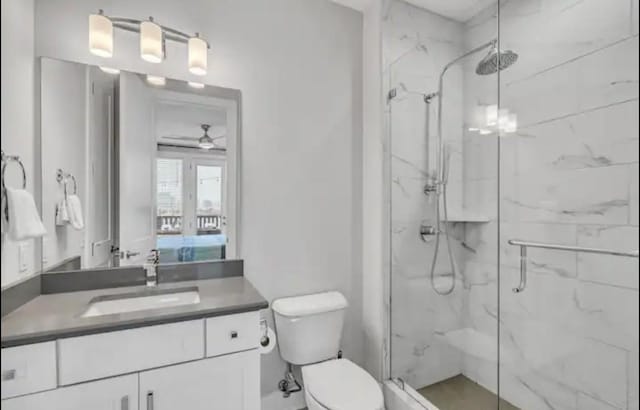 bathroom with ceiling fan, vanity, toilet, and an enclosed shower