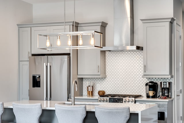 kitchen featuring pendant lighting, stainless steel fridge with ice dispenser, backsplash, and wall chimney exhaust hood