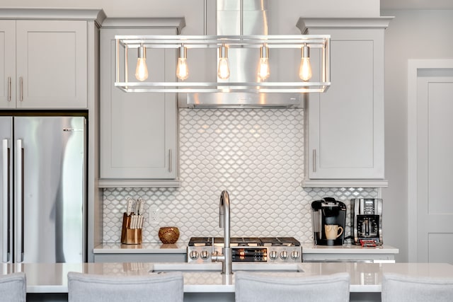 kitchen with backsplash, hanging light fixtures, stainless steel refrigerator, and a kitchen bar