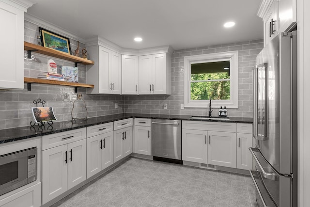 kitchen with decorative backsplash, white cabinetry, sink, and appliances with stainless steel finishes