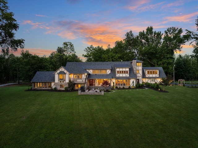 back house at dusk featuring a yard and a patio