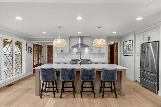 kitchen featuring wall chimney exhaust hood, a spacious island, hanging light fixtures, and high end refrigerator