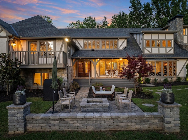 back house at dusk featuring a patio and a balcony