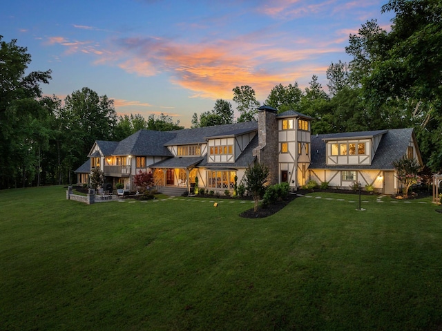 back house at dusk with a yard and a patio