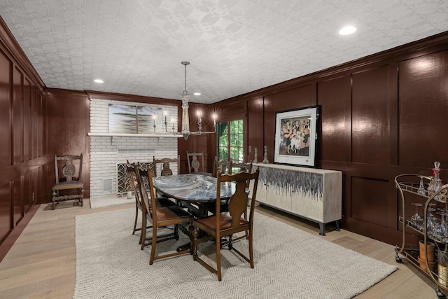 dining area featuring radiator, wood walls, a fireplace, and light hardwood / wood-style flooring