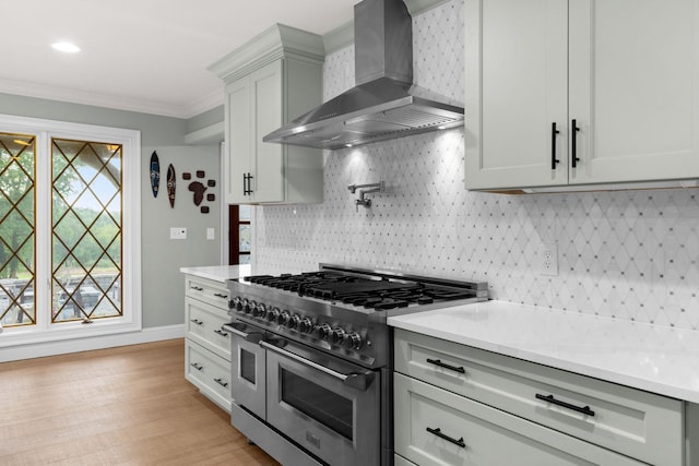 kitchen with decorative backsplash, range with two ovens, ornamental molding, and wall chimney range hood