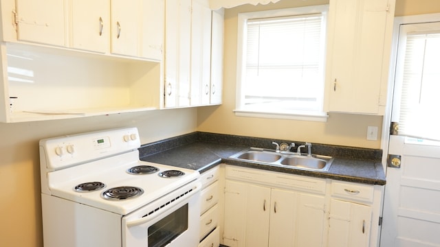 kitchen with sink, electric stove, and white cabinets