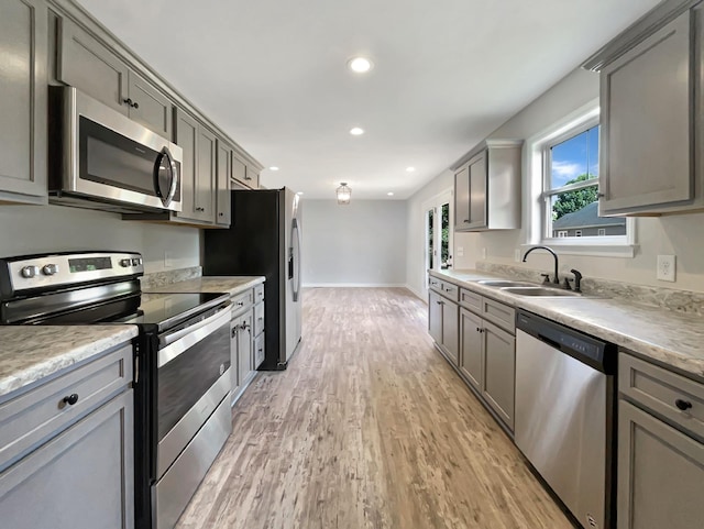 kitchen featuring stainless steel appliances, sink, light hardwood / wood-style floors, and gray cabinetry