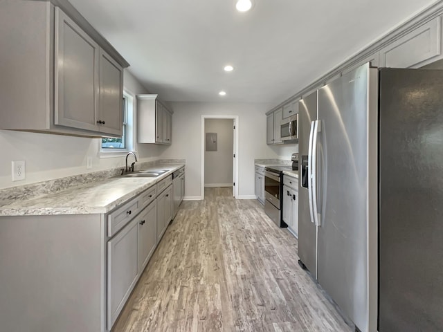 kitchen with appliances with stainless steel finishes, light hardwood / wood-style floors, gray cabinets, and sink