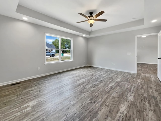 spare room with ceiling fan, a raised ceiling, and dark hardwood / wood-style floors