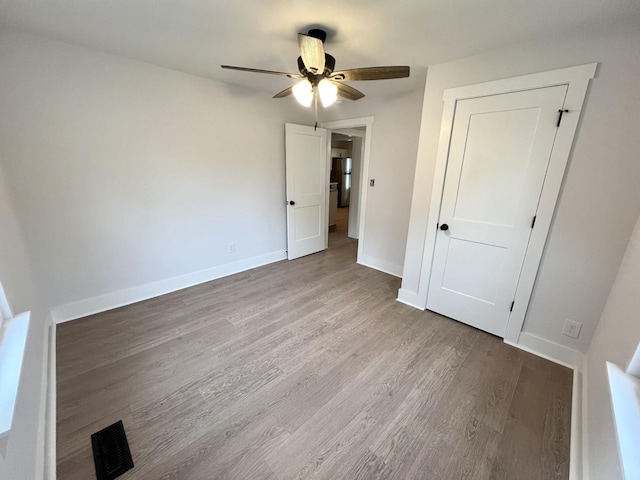 unfurnished bedroom with stainless steel refrigerator, ceiling fan, and light wood-type flooring