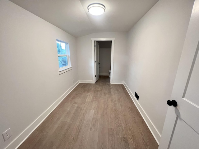 unfurnished room featuring wood-type flooring and vaulted ceiling