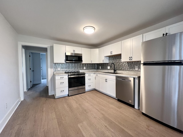 kitchen with appliances with stainless steel finishes, sink, white cabinets, and decorative backsplash