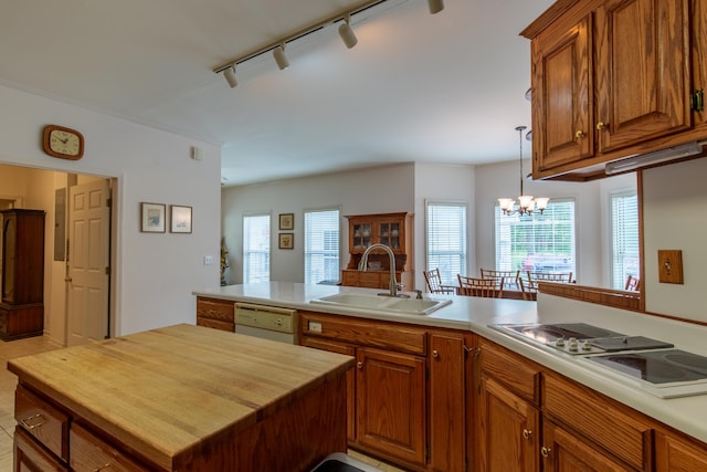 kitchen featuring a notable chandelier, dishwasher, track lighting, gas cooktop, and sink