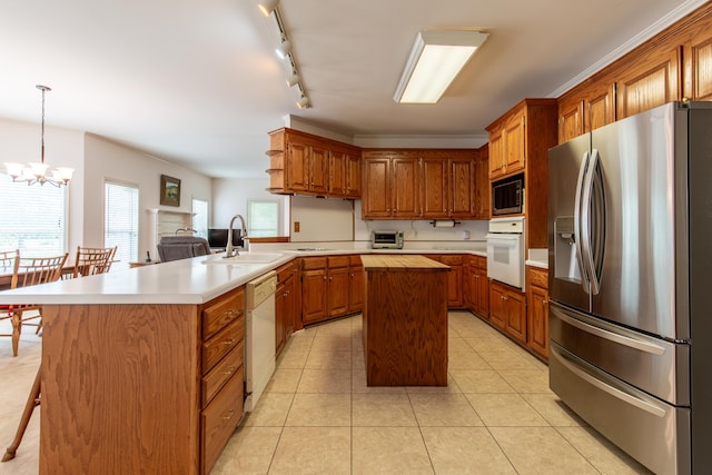 kitchen featuring a notable chandelier, hanging light fixtures, white appliances, sink, and a kitchen island